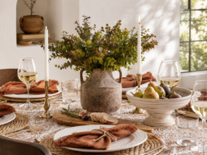 Mediterranean fall table with olive rust colored linens, natural wood, woven textures, brass candle holders and creamy taper candles
